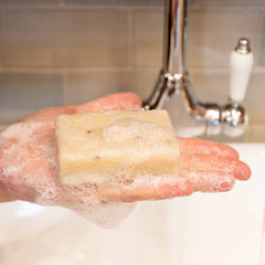 A Mull heather soap with lots of lather bubbles sitting on a hand at our soap station where you can try before you buy at the Isle of Mull soap co shop in Tobermory. 