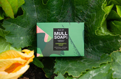 a gardeners soap box sitting in a big green leaf. The box is dark green and bold leaf design. The soap is medicinal, healing and a mild exfoliant. Handmade in Tobermory by the Isle of Mull soap co.  