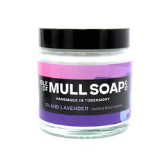 A glass jar with black lid. colourful purple and pink label design, filled with island lavender hand and body cream handmade in Tobermory by the Isle of Mull soap co. 
