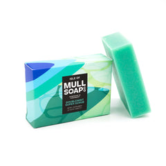 a double mint super scrub box sitting next to the blue soap bar. The box is a blue and green design. The soap is described as very scrubby and very minty! Handmade in Tobermory by the Isle of Mull soap co.  