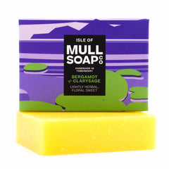 a bergamot and clary sage soap box sitting on the soap bar. The box is a purple and green design. The soap is described as lightly herbal, floral sweet. Handmade in Tobermory by the Isle of Mull soap co.  